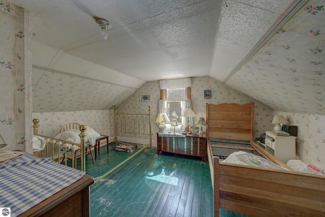 bedroom featuring hardwood / wood-style floors, wallpapered walls, and lofted ceiling