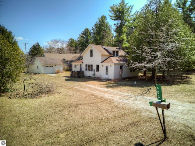 view of front of house featuring a shingled roof, a chimney, a garage, and dirt driveway