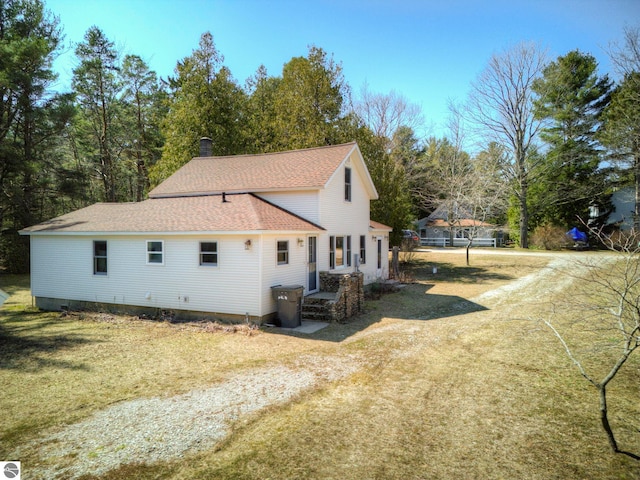 view of property exterior featuring a yard and a shingled roof