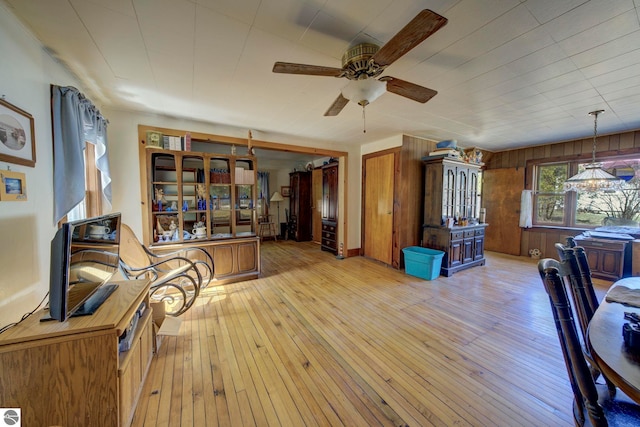 interior space with wood walls, light wood-style flooring, and a ceiling fan