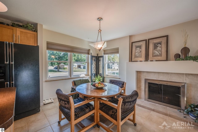 dining area featuring light tile patterned flooring and a tiled fireplace