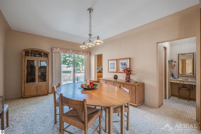 dining space with a chandelier, baseboards, and light colored carpet