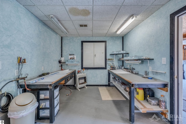 misc room with concrete floors, visible vents, a workshop area, a textured wall, and a paneled ceiling