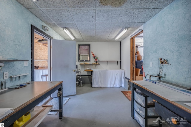 interior space featuring a textured wall and a drop ceiling