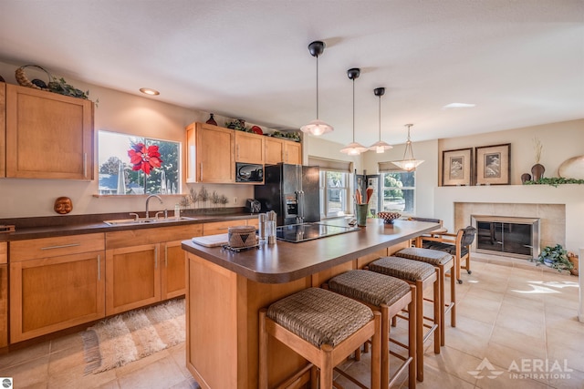 kitchen with black appliances, dark countertops, a kitchen breakfast bar, and a sink
