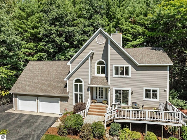 2127 E Timberlane Dr, Traverse City, MI 49686 - view of front of home with a shingled roof, a deck, a garage, a chimney, and driveway