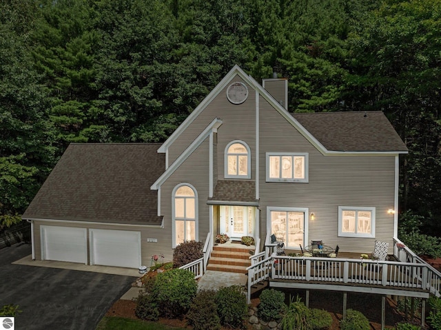 2127 E Timberlane Dr, Traverse City, MI 49686 - view of front of house with driveway, a shingled roof, a garage, and a chimney