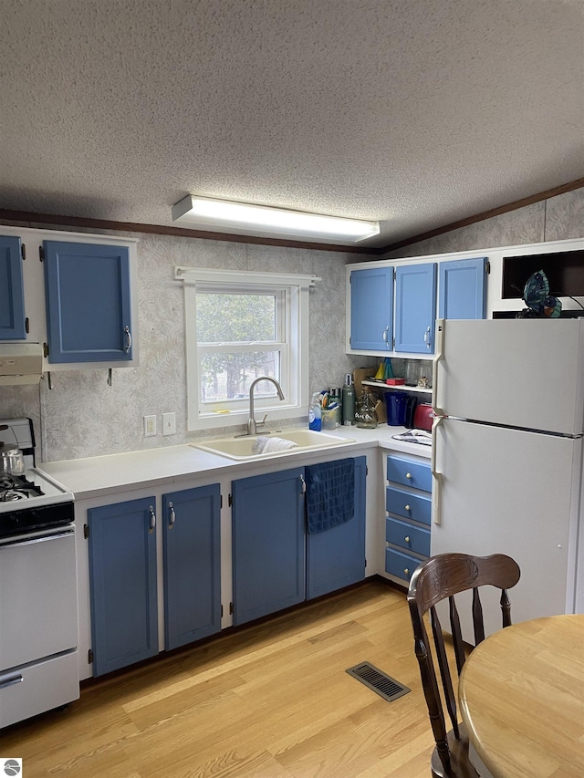 kitchen featuring blue cabinets, white appliances, a sink, a textured ceiling, and light wood-type flooring