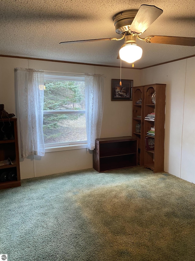 carpeted empty room featuring a textured ceiling, ceiling fan, and crown molding