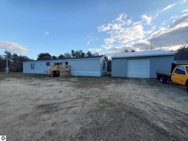 view of front of house with an outdoor structure, a detached garage, and dirt driveway