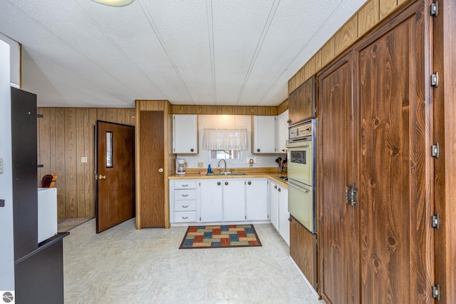 kitchen featuring white cabinets, a warming drawer, a sink, light countertops, and oven