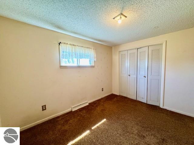 1705 S State Rd, Ithaca, MI 48847 - unfurnished bedroom with carpet, a textured ceiling, a closet, visible vents, and baseboards