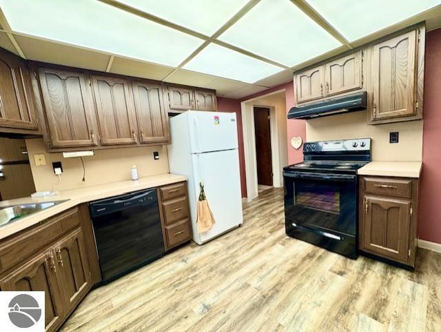 1705 S State Rd, Ithaca, MI 48847 - kitchen with under cabinet range hood, light wood finished floors, light countertops, and black appliances