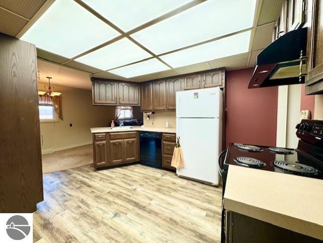 1705 S State Rd, Ithaca, MI 48847 - kitchen featuring baseboards, light countertops, light wood-type flooring, under cabinet range hood, and black appliances