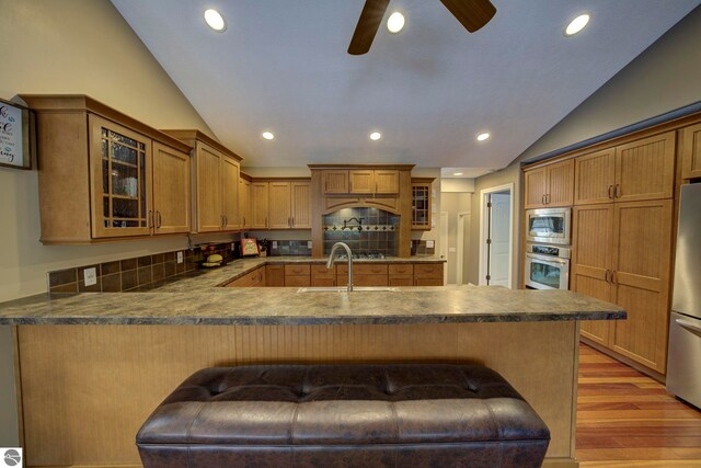 kitchen featuring vaulted ceiling, recessed lighting, a peninsula, dark countertops, and appliances with stainless steel finishes