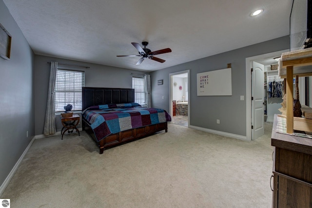 bedroom featuring light carpet, baseboards, a walk in closet, and connected bathroom