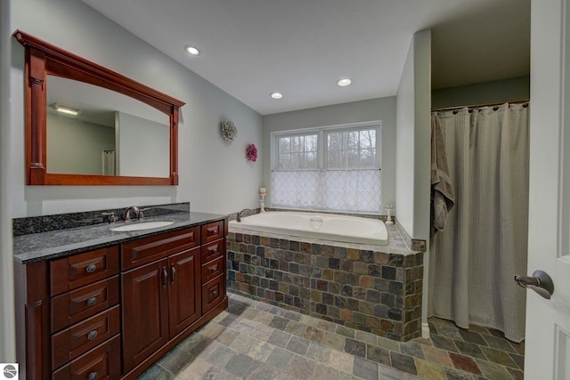 full bathroom featuring a garden tub, vanity, stone finish flooring, and recessed lighting