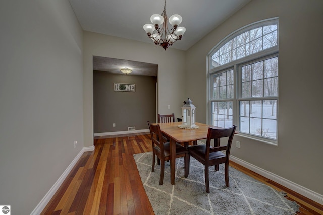 dining space featuring wood-type flooring, baseboards, and a chandelier