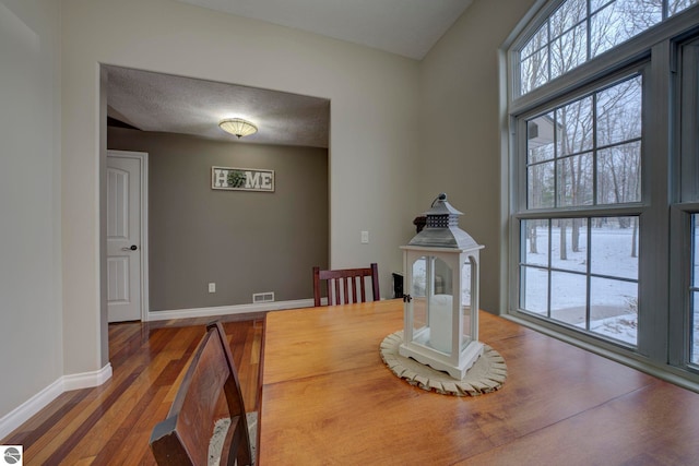 dining area with wood finished floors, baseboards, and visible vents