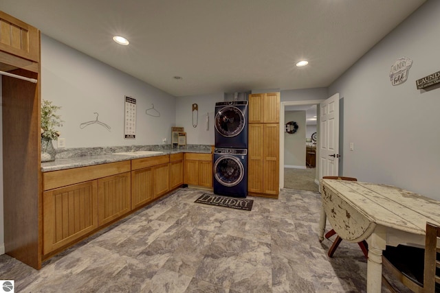 washroom featuring stacked washing maching and dryer, cabinet space, and recessed lighting