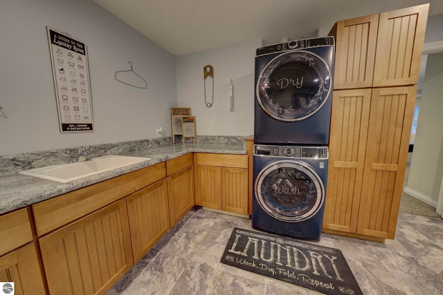 laundry area with a sink, cabinet space, and stacked washing maching and dryer