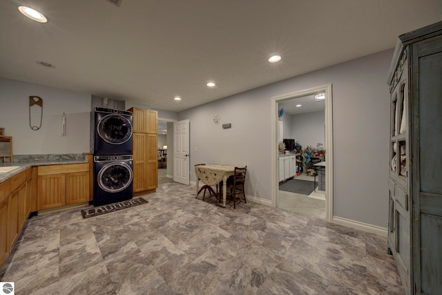clothes washing area with recessed lighting, stacked washer and clothes dryer, laundry area, and baseboards