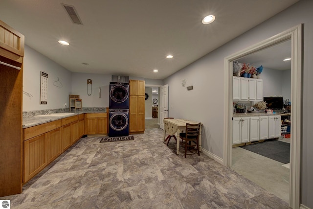 clothes washing area featuring visible vents, baseboards, laundry area, stacked washer and dryer, and recessed lighting