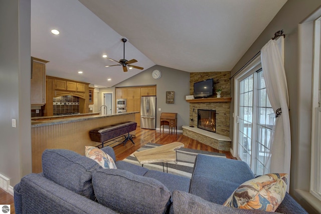 living room with a stone fireplace, a ceiling fan, recessed lighting, light wood finished floors, and lofted ceiling