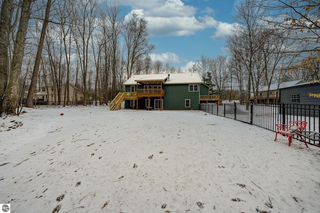 snow covered house featuring stairway, a wooden deck, and fence
