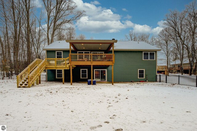 snow covered property with a wooden deck, fence, and stairway