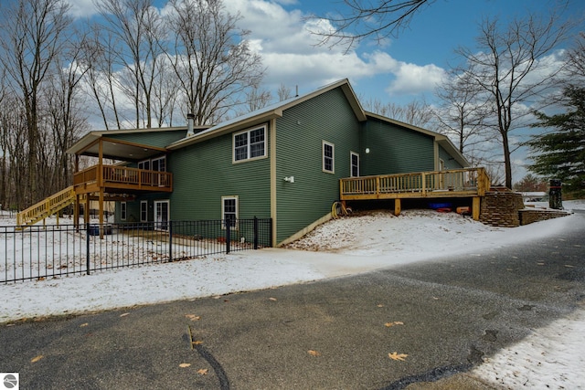 view of snowy exterior featuring fence, a deck, and stairway