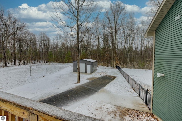 yard covered in snow featuring an outbuilding and a forest view