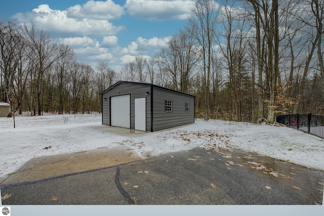 snow covered garage with a garage and fence