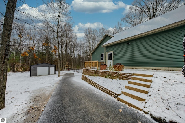 view of snowy exterior featuring a garage and an outbuilding