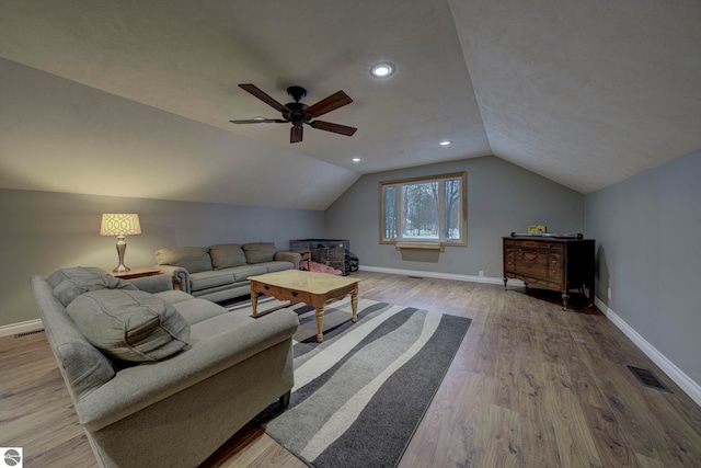 living room with ceiling fan, vaulted ceiling, visible vents, wood finished floors, and baseboards