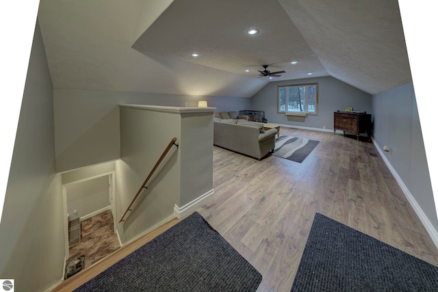 interior space featuring light wood-style floors, baseboards, a ceiling fan, and vaulted ceiling
