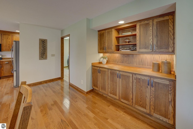 1339 Killdeer Ln, Kingsley, MI 49649 - kitchen featuring open shelves, light countertops, freestanding refrigerator, brown cabinets, and light wood finished floors