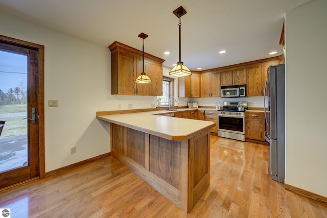 1339 Killdeer Ln, Kingsley, MI 49649 - kitchen with a sink, a peninsula, brown cabinets, light wood finished floors, and stainless steel appliances