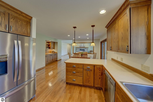 1339 Killdeer Ln, Kingsley, MI 49649 - kitchen with hanging light fixtures, light wood-type flooring, a peninsula, brown cabinets, and stainless steel appliances