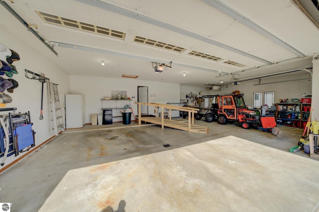 1339 Killdeer Ln, Kingsley, MI 49649 - garage with freestanding refrigerator, a garage door opener, and a workshop area