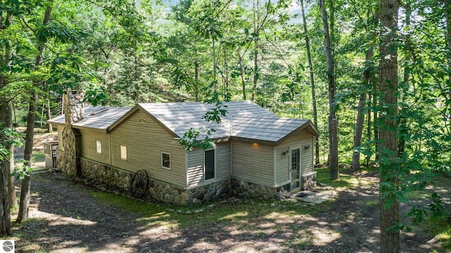 view of home's exterior featuring a forest view and a chimney
