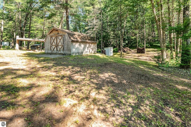 view of yard featuring a wooded view, an outbuilding, and a storage unit