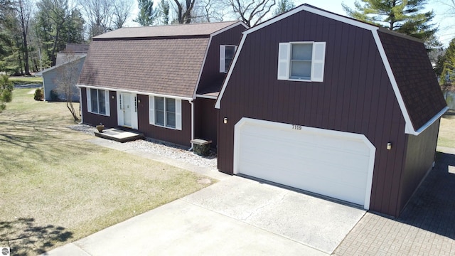 7119 Lakewood Dr, Oscoda, MI 48750 - colonial inspired home with an attached garage, a front lawn, a gambrel roof, driveway, and roof with shingles
