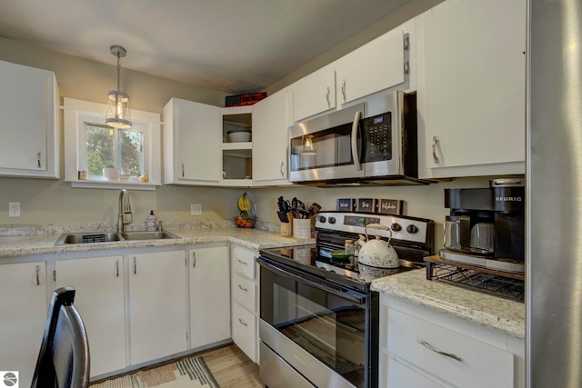 kitchen with white cabinets, light wood-style flooring, a sink, light countertops, and appliances with stainless steel finishes