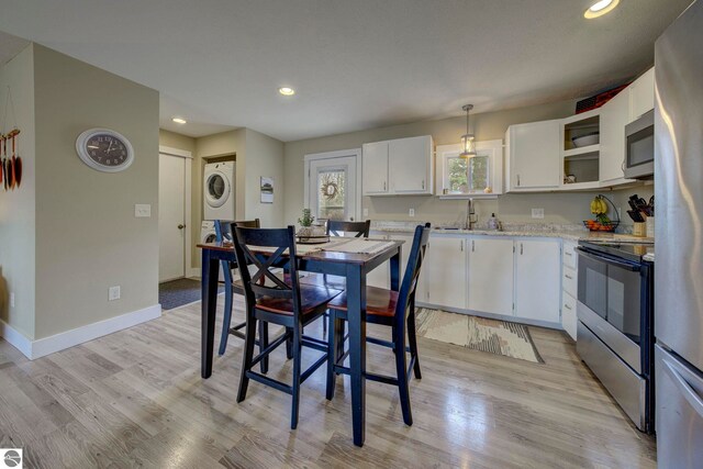 dining room featuring baseboards, light wood-style flooring, stacked washer / drying machine, and recessed lighting