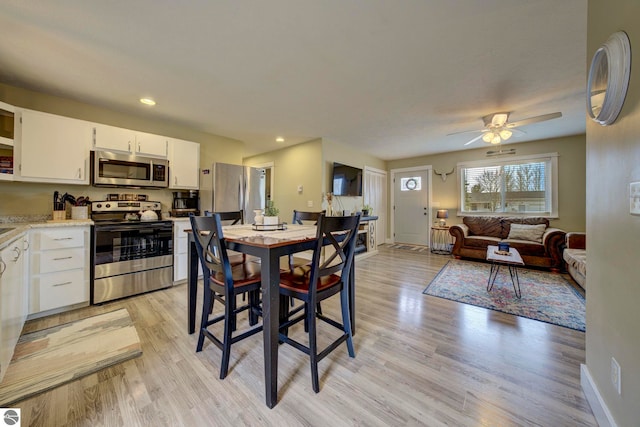 dining room with a ceiling fan, baseboards, and light wood-style floors