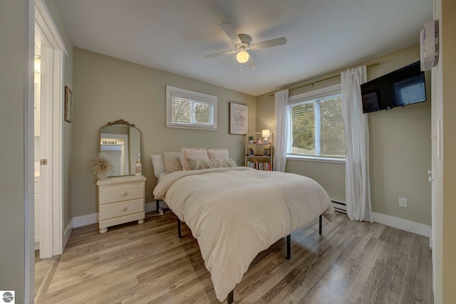 bedroom with baseboard heating, baseboards, a ceiling fan, and light wood finished floors