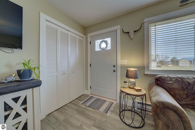 foyer featuring baseboards, light wood finished floors, and baseboard heating