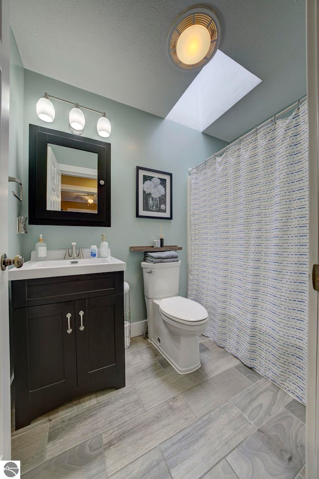 bathroom featuring a skylight, a shower with curtain, vanity, and toilet