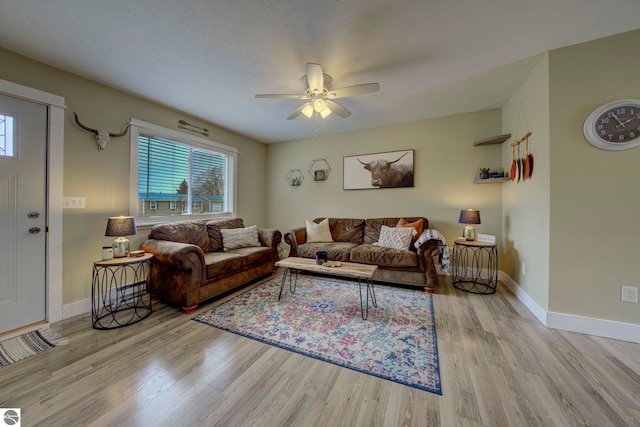 living room featuring baseboards, a ceiling fan, and wood finished floors